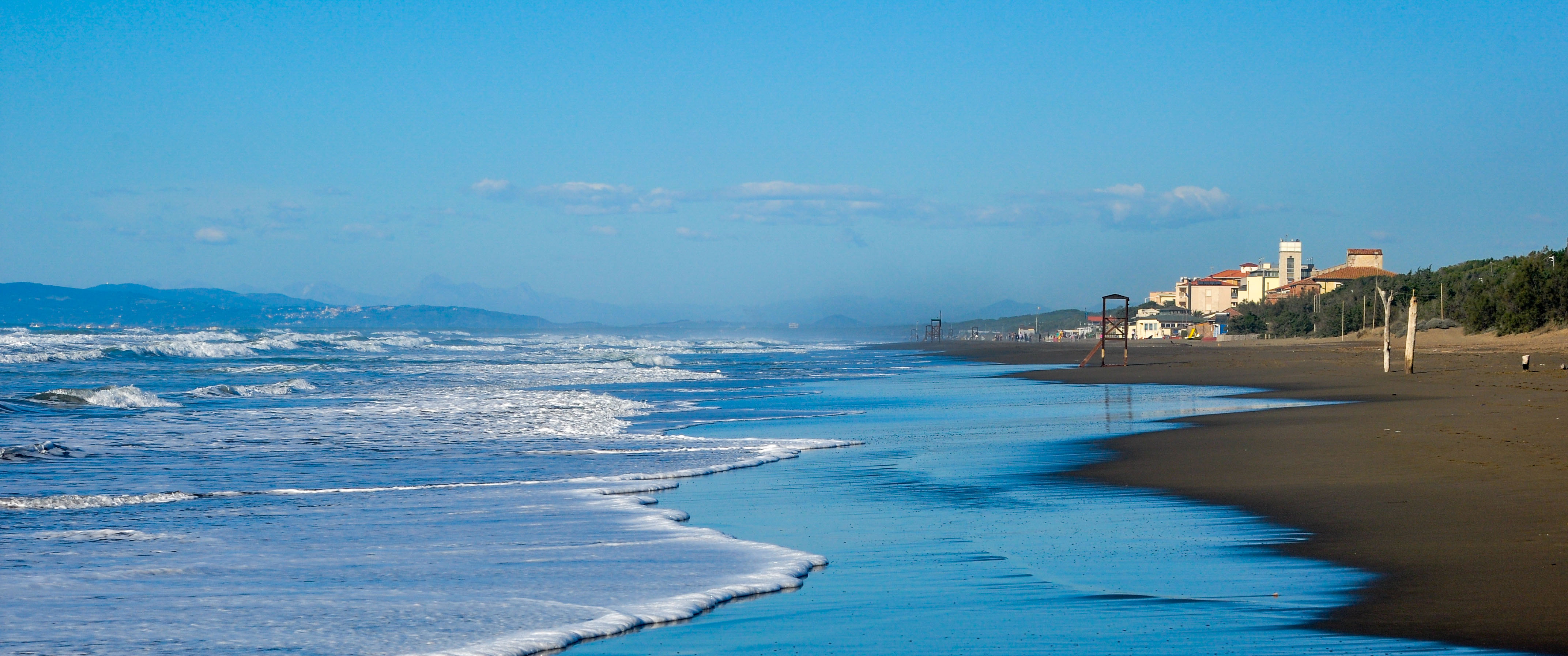 Le onde sulla battigia e le ville lungo la spiaggia.